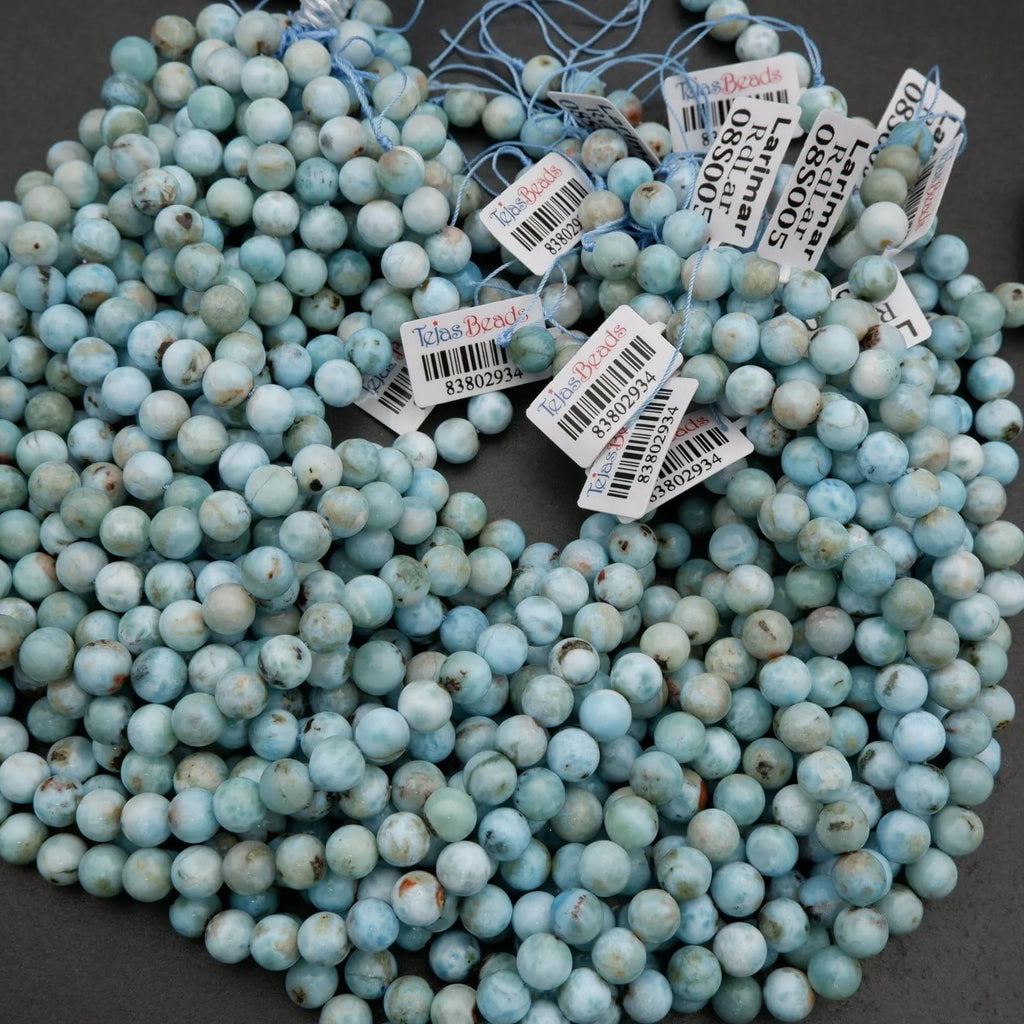 Strands of Larimar beads featuring pale blue ocean-like swirls and natural inclusions