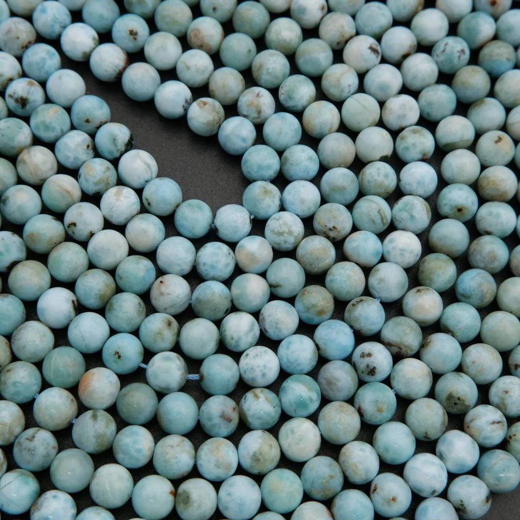 Strands of Larimar beads featuring pale blue ocean-like swirls and natural inclusions