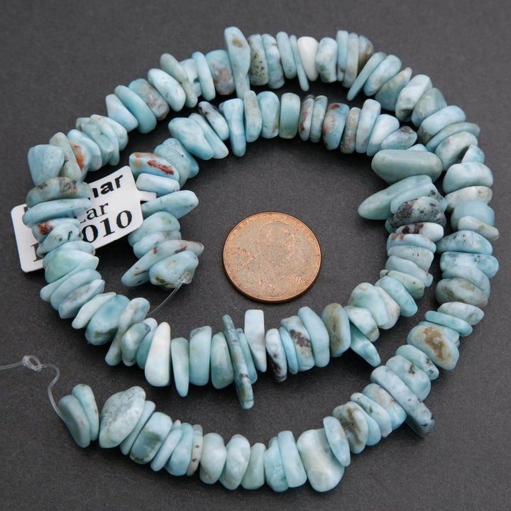 String of blue beads with a penny for scale on a dark surface