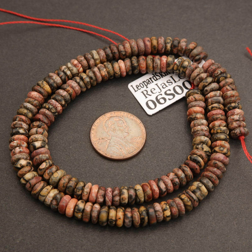 Necklace of multicolored beads with a penny for scale on a dark surface