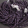 Purple beads with visible tags on a dark background