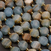 Close-up of faceted gemstone beads with gold spacers on a dark surface