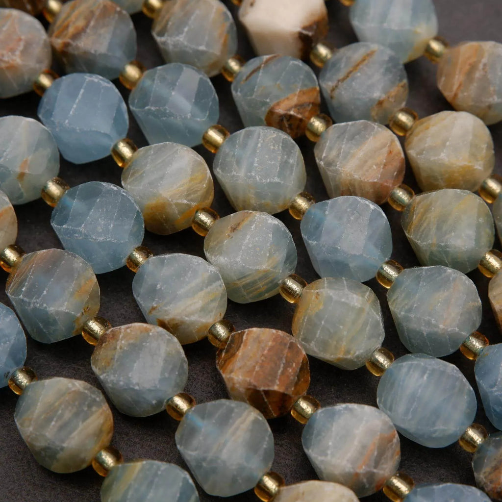 Close-up of faceted gemstone beads with gold spacers on a dark surface