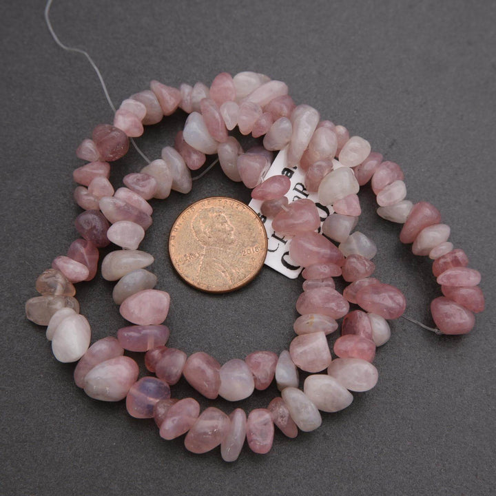 String of pink beads with a coin for scale on a gray background
