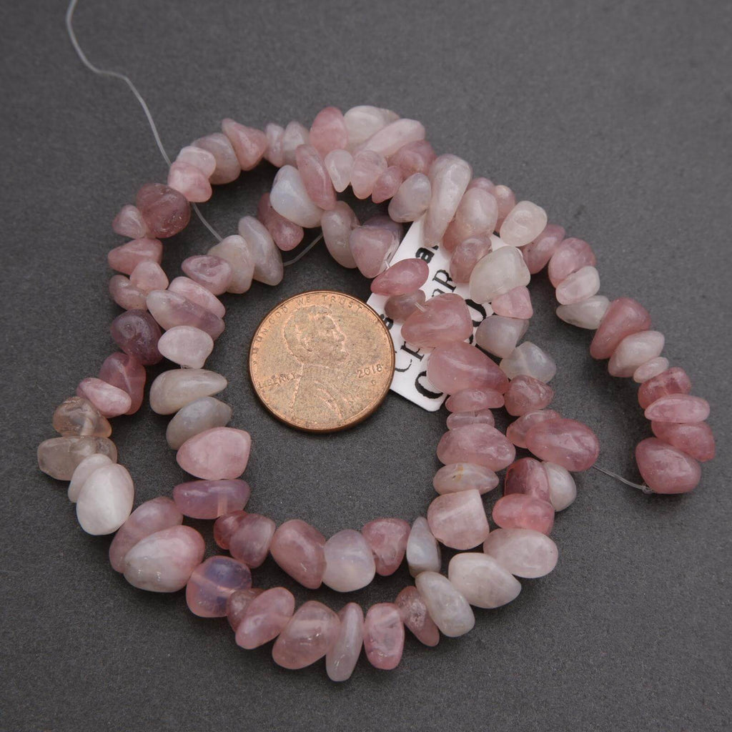 String of pink beads with a coin for scale on a gray background