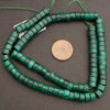 Green beaded necklace with a coin for scale on a gray background