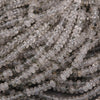 Close-up of clear quartz beads with black specks on a dark background.