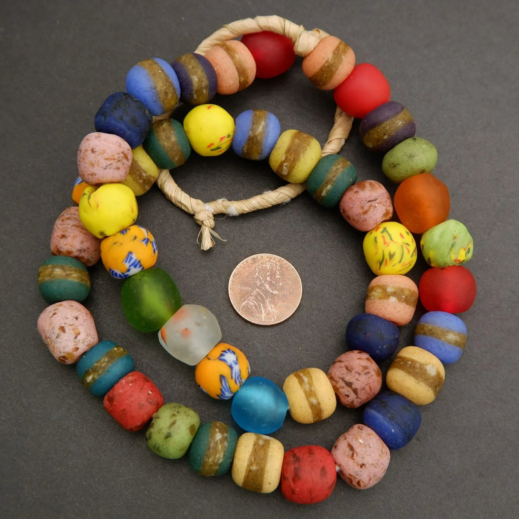 Colorful beaded bracelet with a penny for scale on a gray background