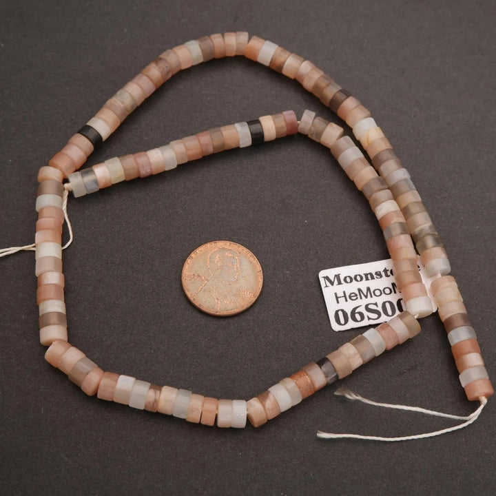 String of multicolored beads with a coin for scale on a dark surface