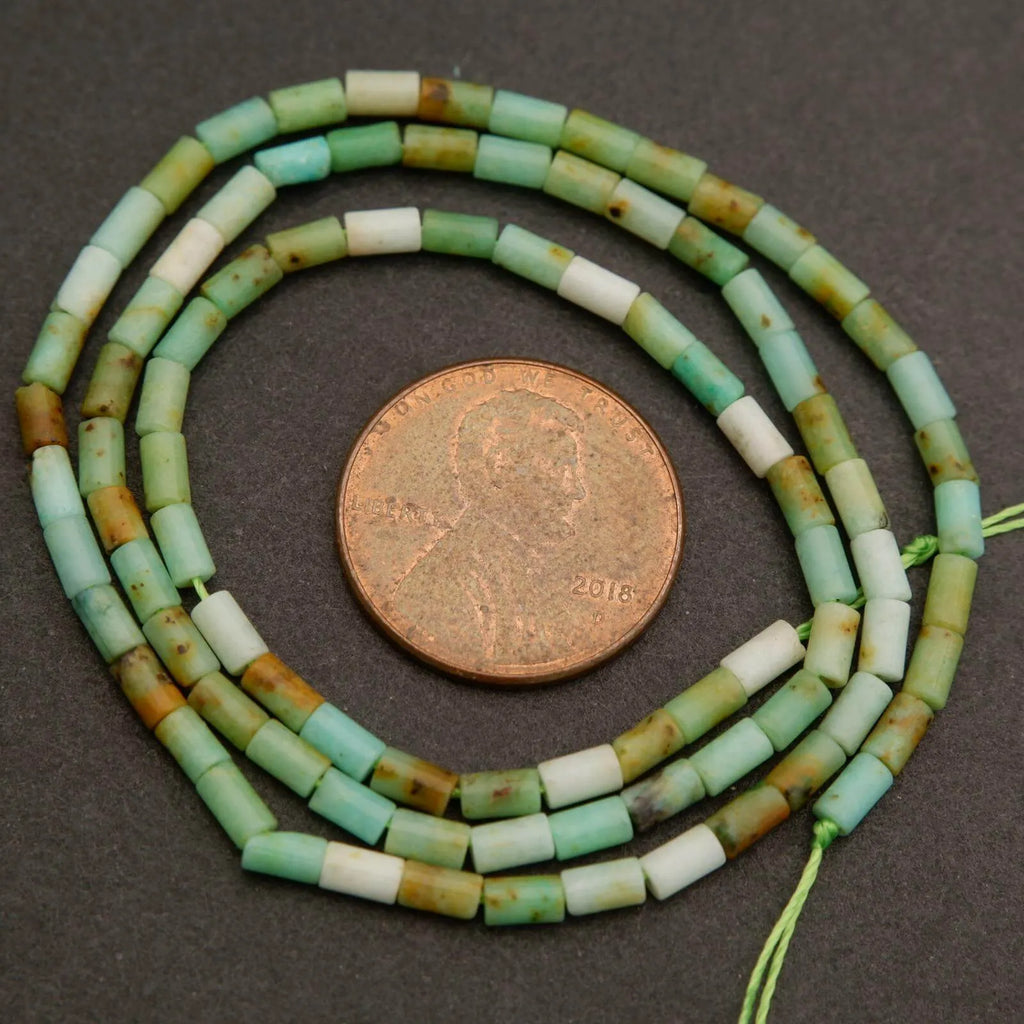 String of green and white beads with a penny for scale on a dark surface