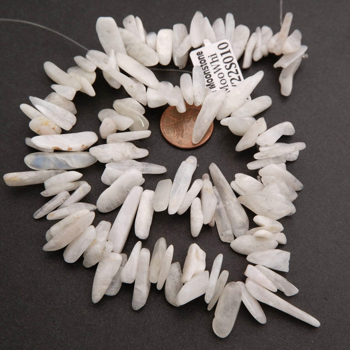 White stone chips arranged in a circular pattern with a penny for scale on a dark background