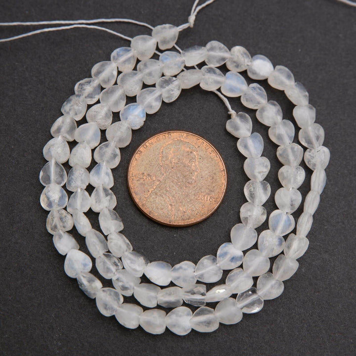 String of clear beads with a penny for size comparison on a dark background