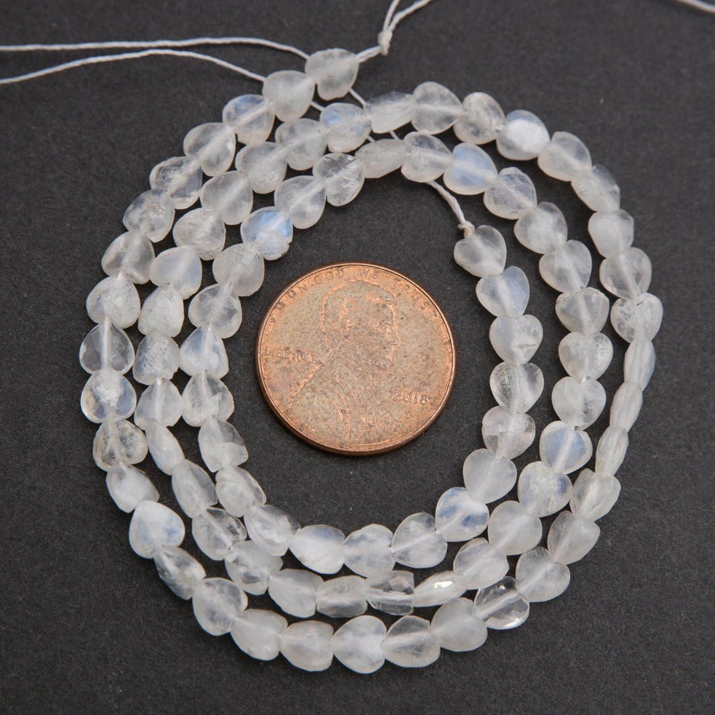 String of clear beads with a penny for size comparison on a dark background