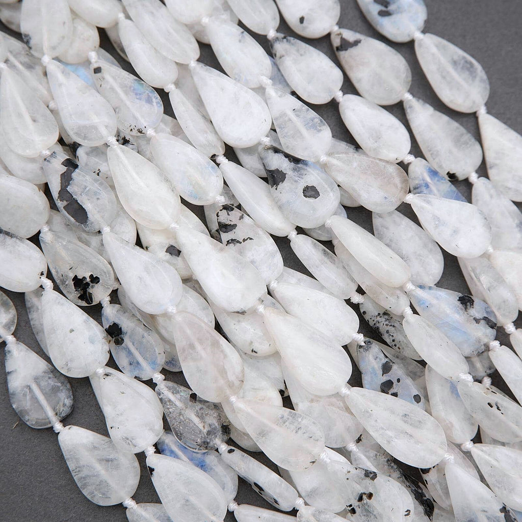 Close-up of white teardrop-shaped beads with blue and black specks on a dark background