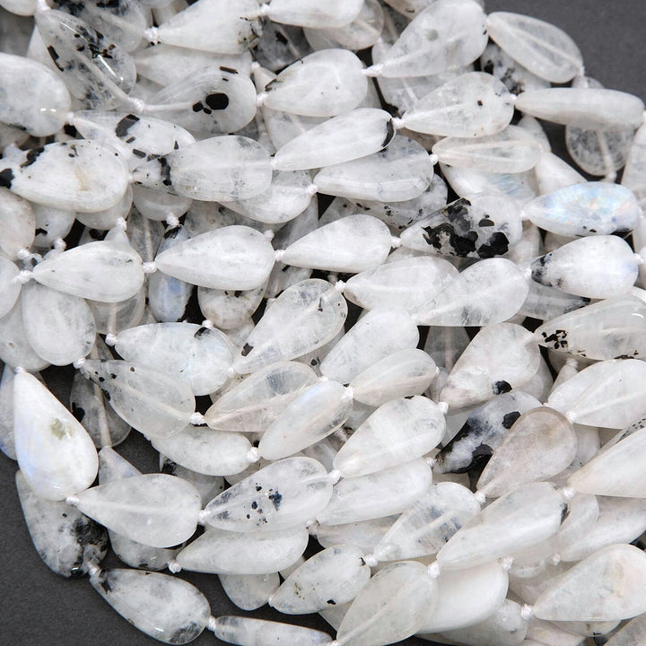 Close-up of white teardrop-shaped beads with black specks on a dark background