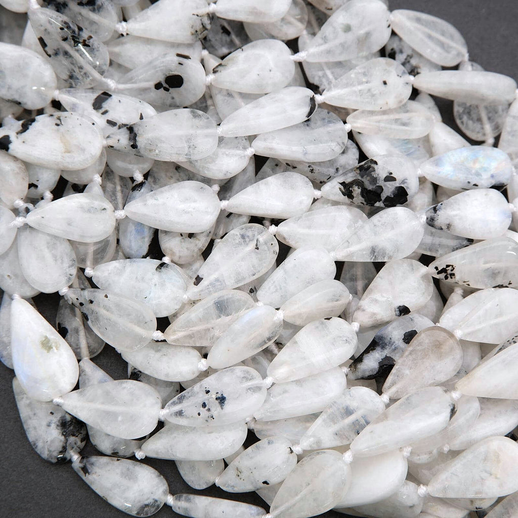 Close-up of white teardrop-shaped beads with black specks on a dark background