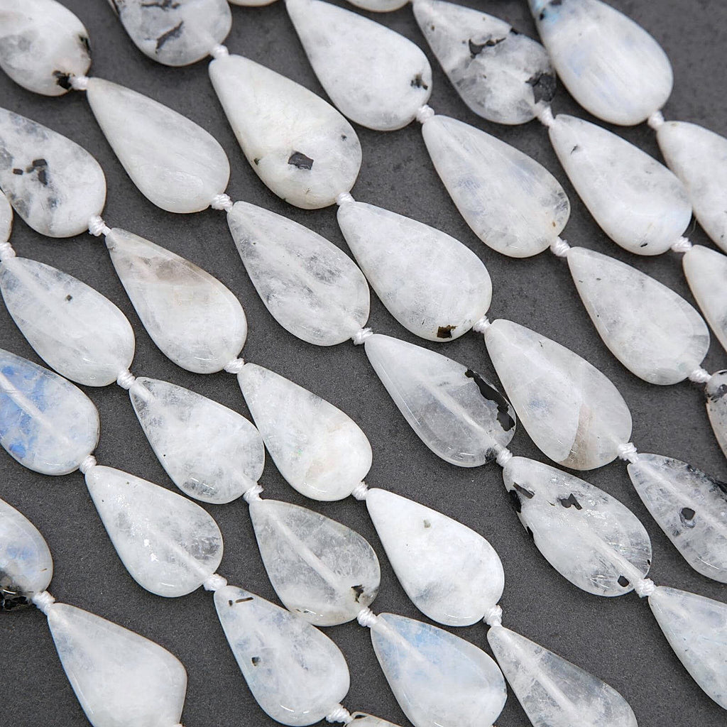Teardrop-shaped white beads on a dark surface