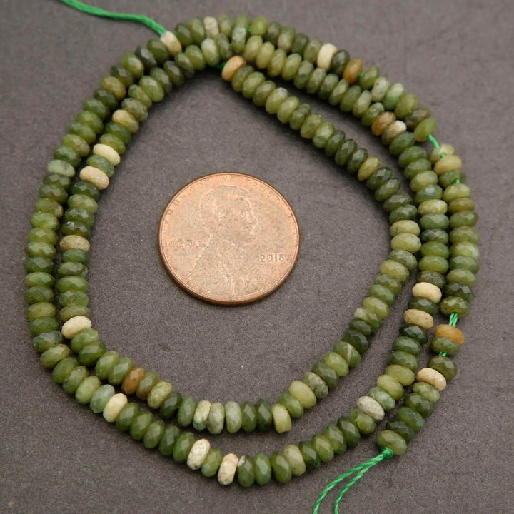 Green bead necklace with a coin for scale on a gray background