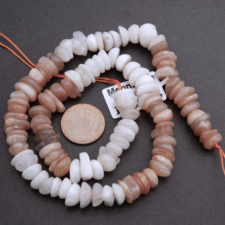 String of multicolored beads with a coin for size comparison on a dark surface