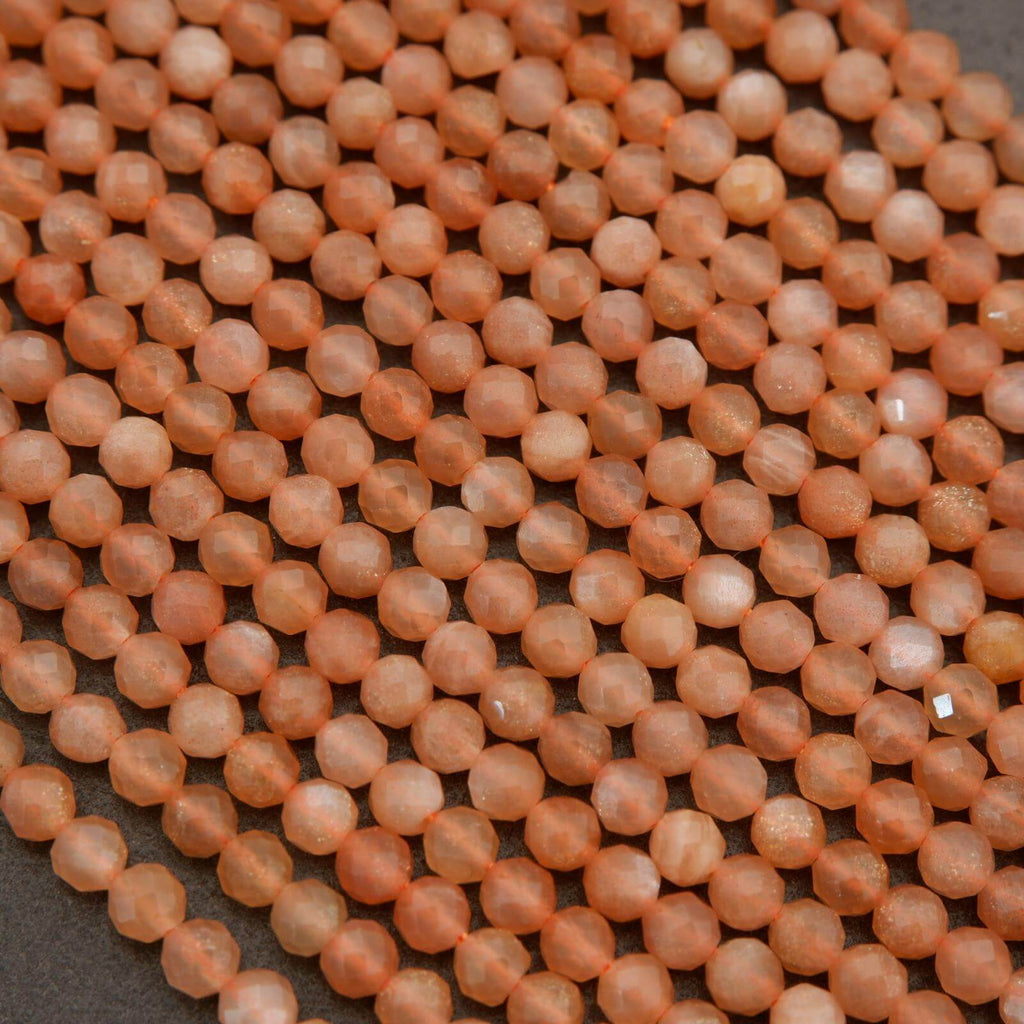 Close-up of small peach-colored beads on a dark surface