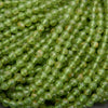 Green round faceted beads with yellow inclusions.