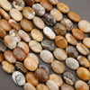 Polished natural stone oval beads in warm earth tones displayed on a dark background.