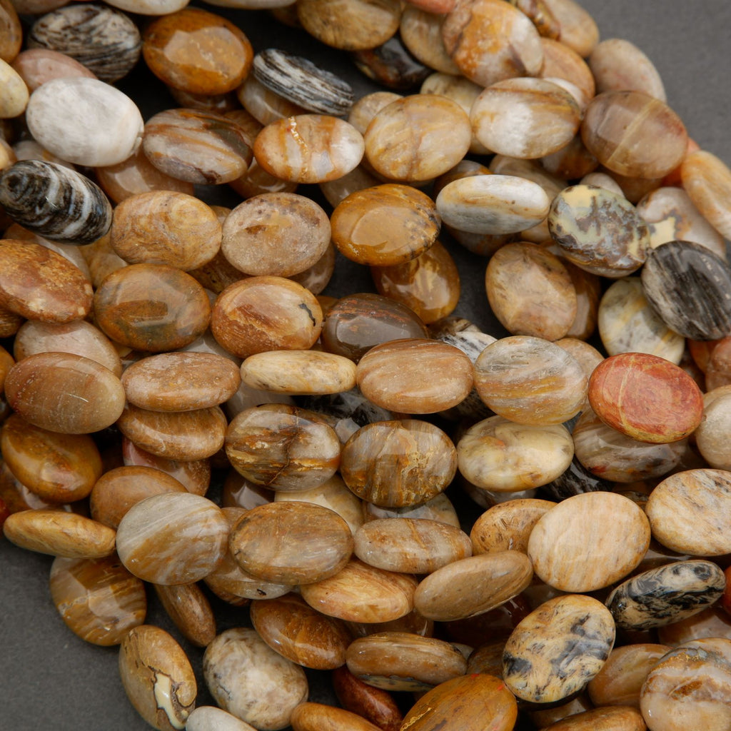 Close-up of smooth oval gemstone beads showing natural color variation in tan, cream, and brown hues.