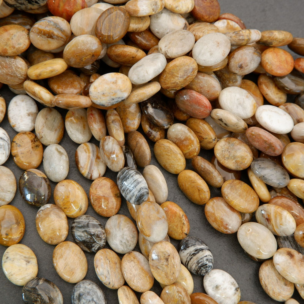 Assorted natural gemstone bead strands featuring oval shapes and warm beige, gold, and brown colors.