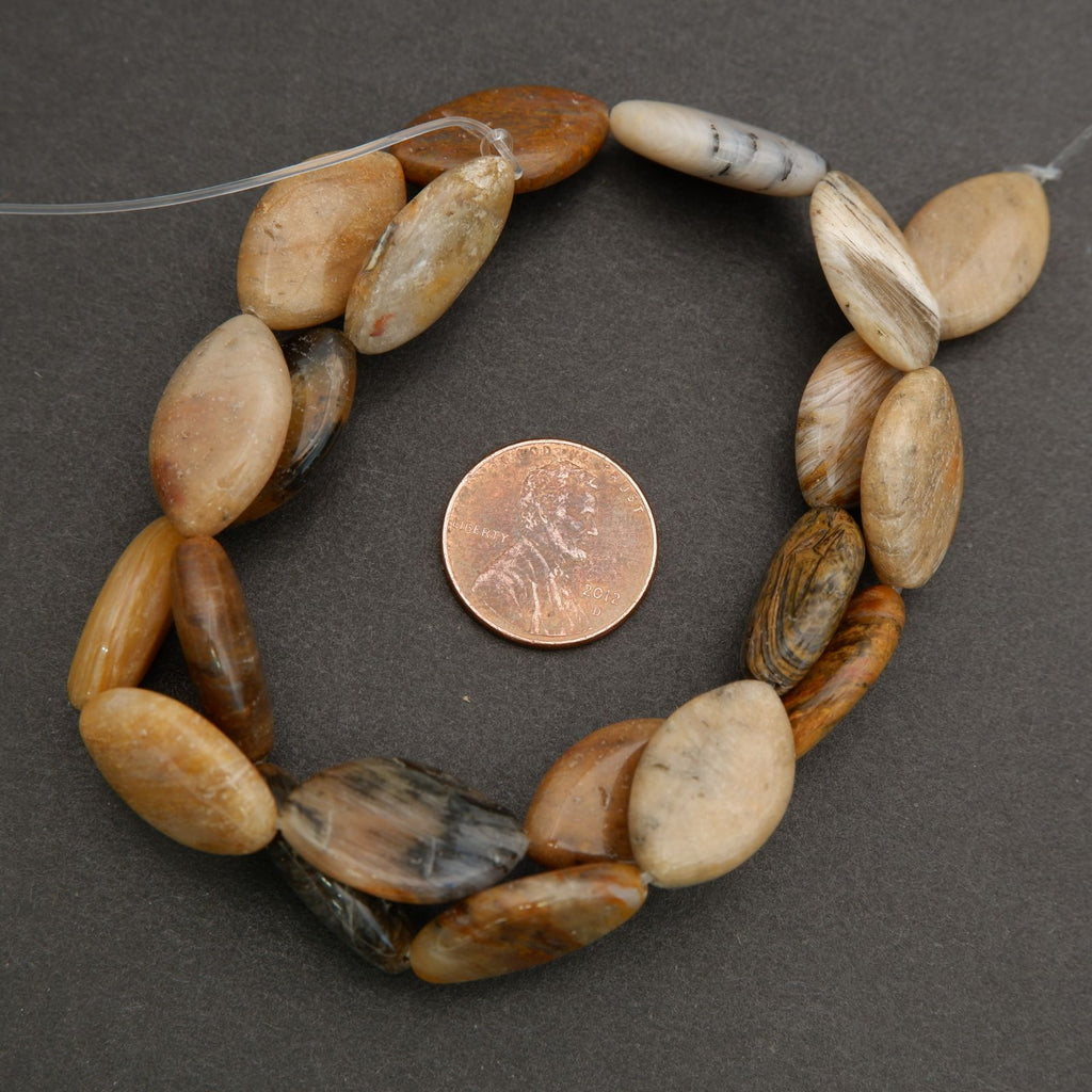 Close-up of polished marquise oval beads showing subtle striations and organic mineral patterns.