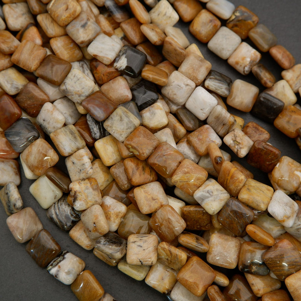 Close-up of mixed natural gemstone beads with smooth square shapes and organic color variation in neutral earth tones.
