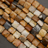 Polished natural stone beads in warm earth tones featuring cream, tan, and golden brown hues on a dark background.