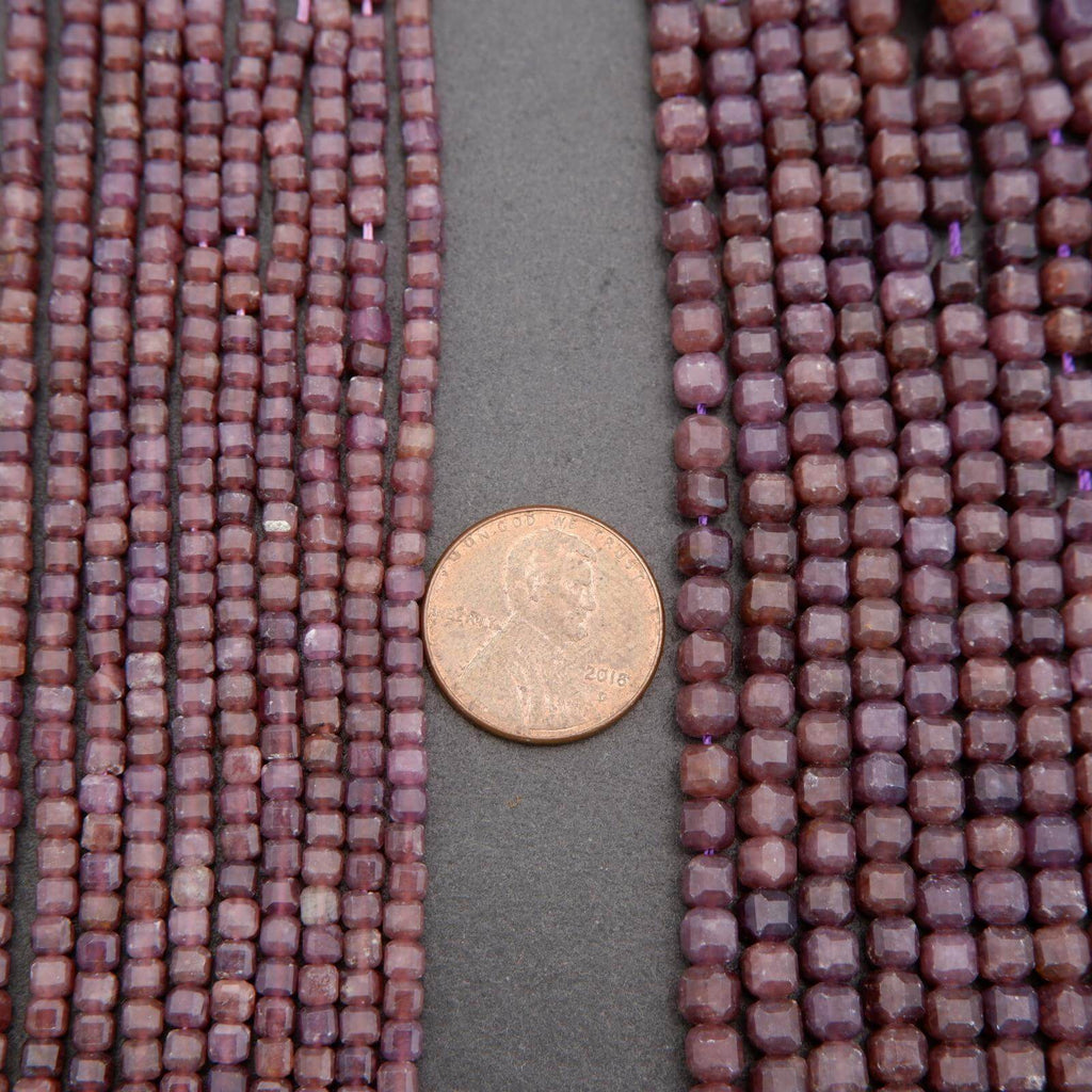Close-up of purple beads with a coin for scale on a gray background