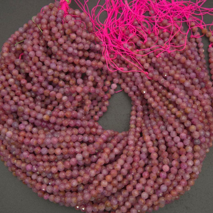 Natural ruby beads in pale pink to deeper rose tones, showcasing characteristic inclusions and a softly reflective surface.