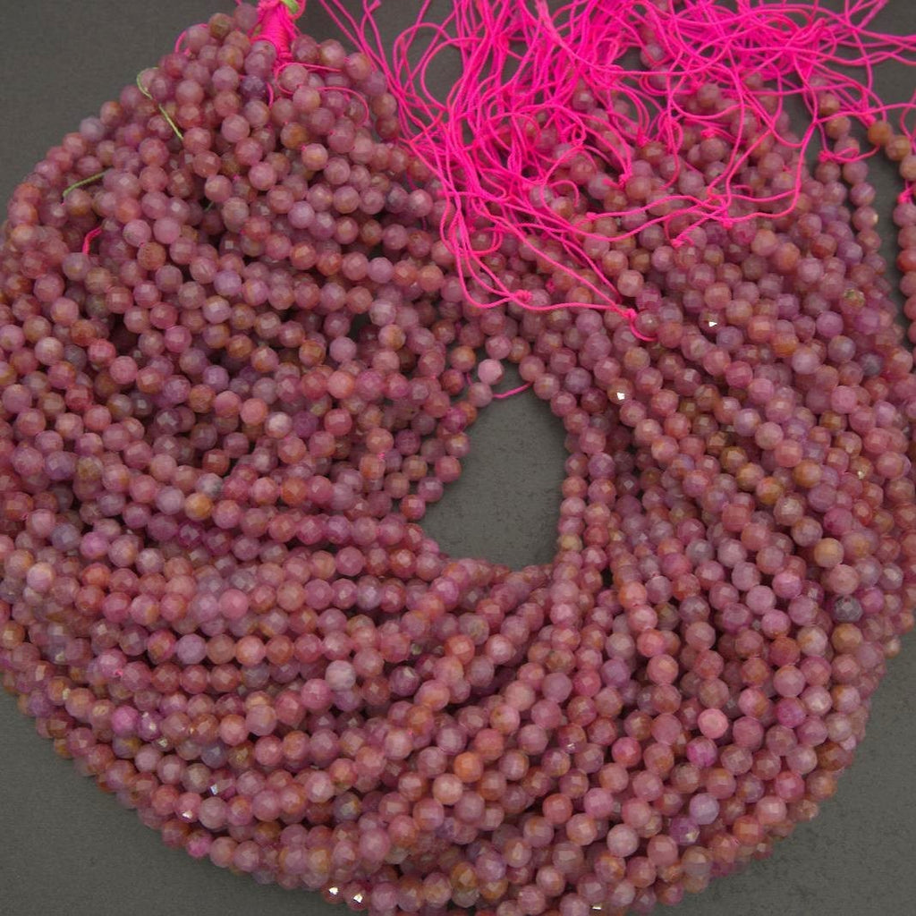 Natural ruby beads in pale pink to deeper rose tones, showcasing characteristic inclusions and a softly reflective surface.