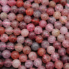 Close-up of pink and red marbled beads on a dark surface