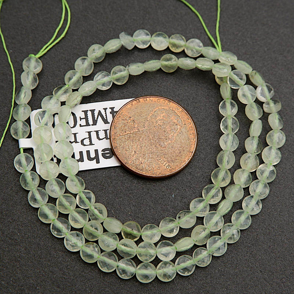 String of green beads with a penny for scale on a dark surface
