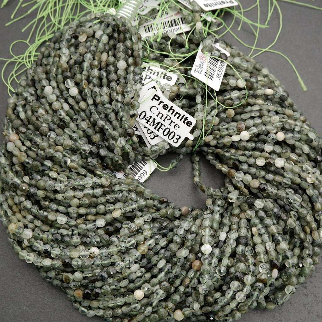 String of green prehnite beads with labels on a gray surface