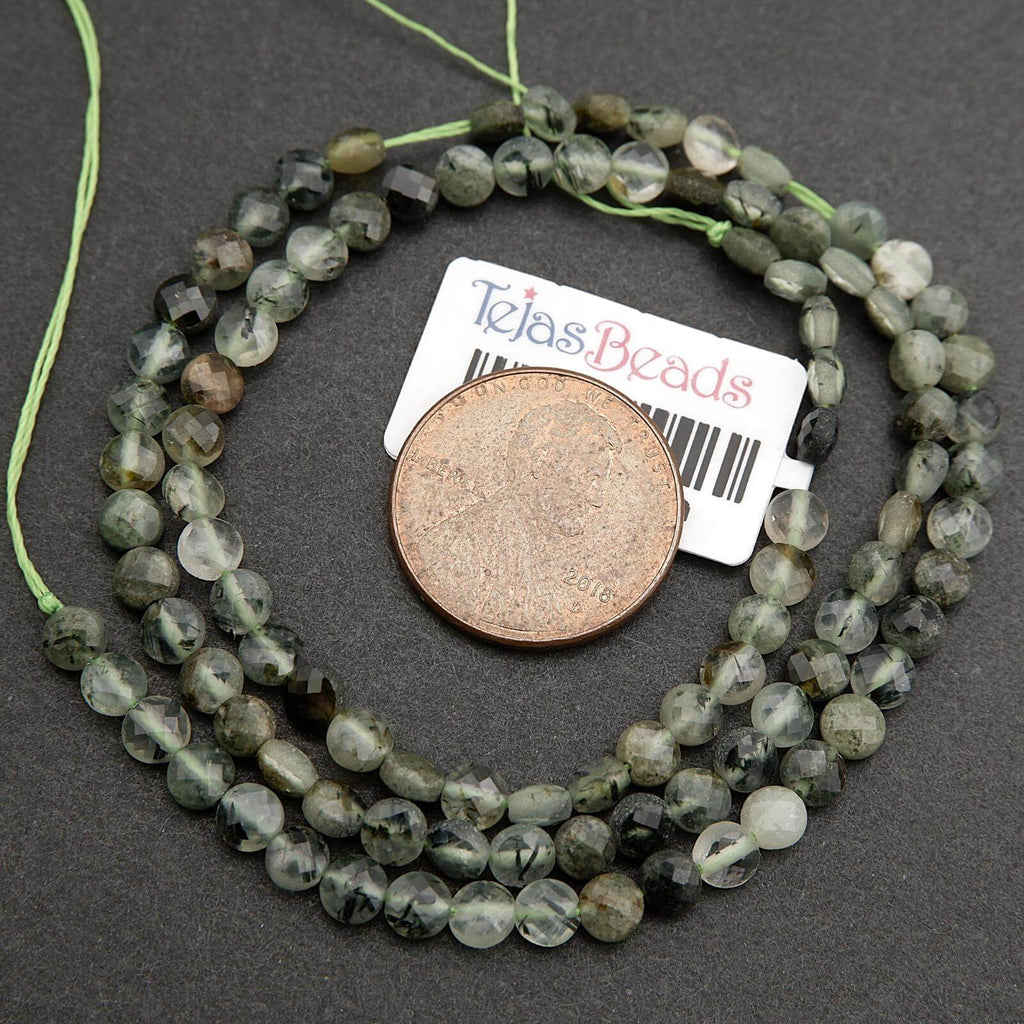 String of green beads with a coin and label on a dark surface