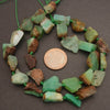 Necklace with green and brown beads next to a penny on a brown background