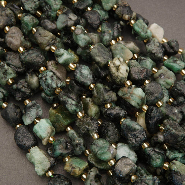 Close-up of green and black stone beads with gold accents on a gray background