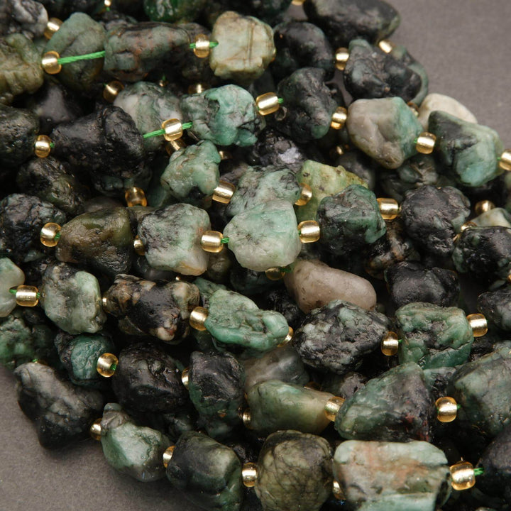 Close-up of green and black stone beads with gold accents on a dark background