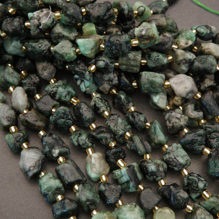 Green stone beads with gold spacers on a gray background