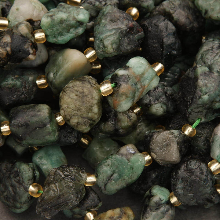 Close-up of green stones with gold beads