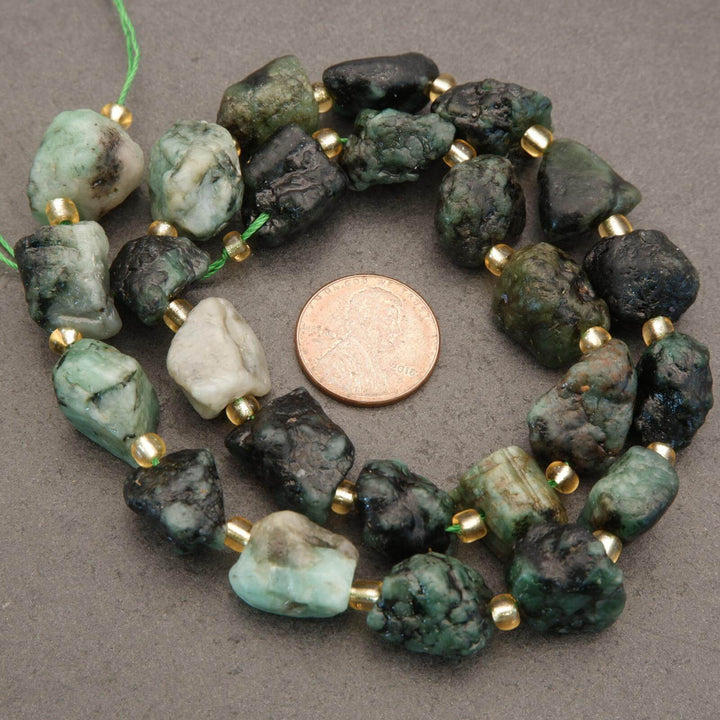 Beaded necklace with green and black stones and gold accents, next to a penny for scale.