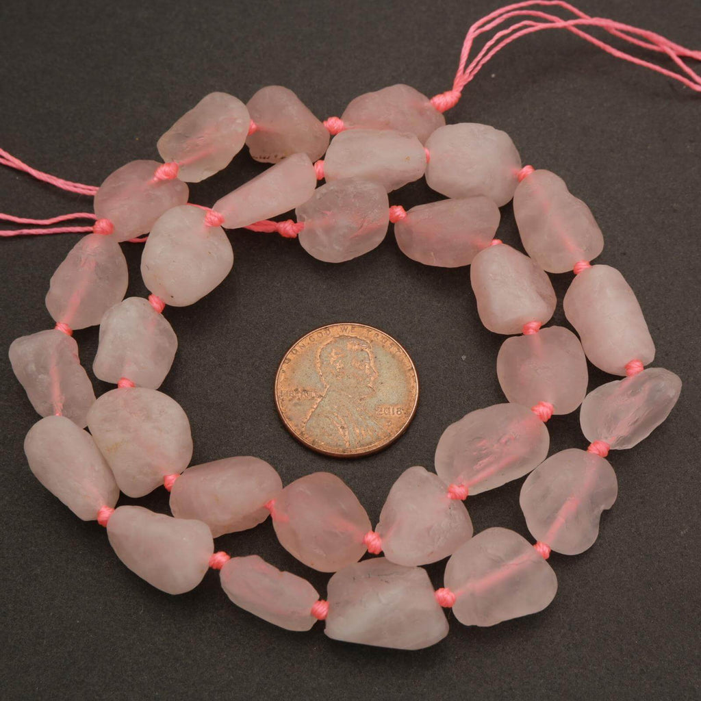 Necklace of pink beads with a coin for scale on a dark background