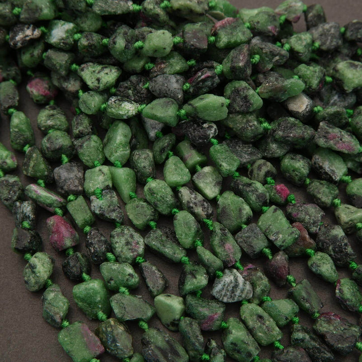 Close-up of green and purple rough gemstones on a dark surface