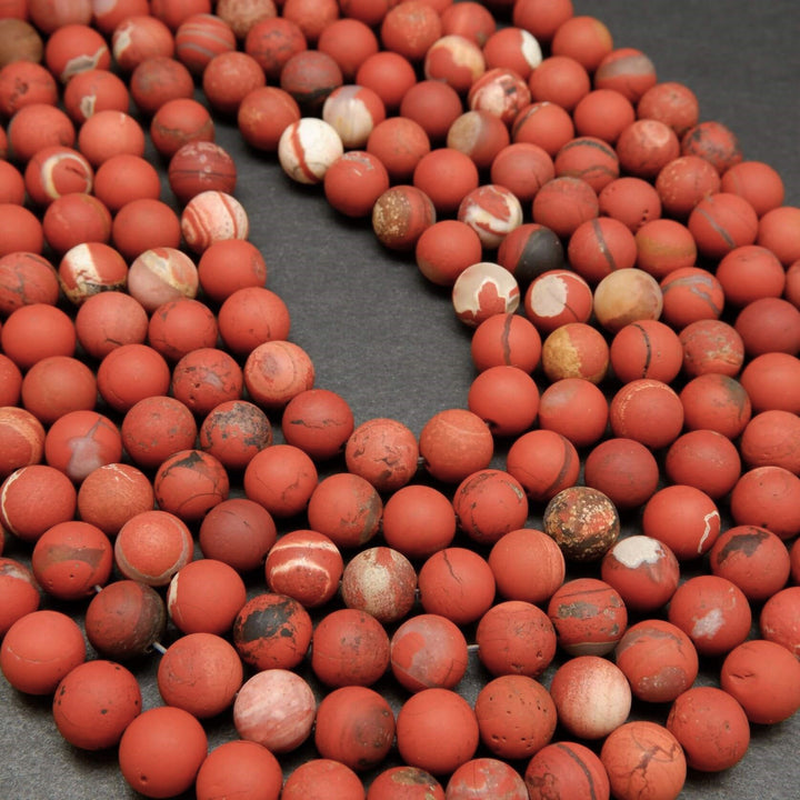 String of red marbled beads on a dark surface