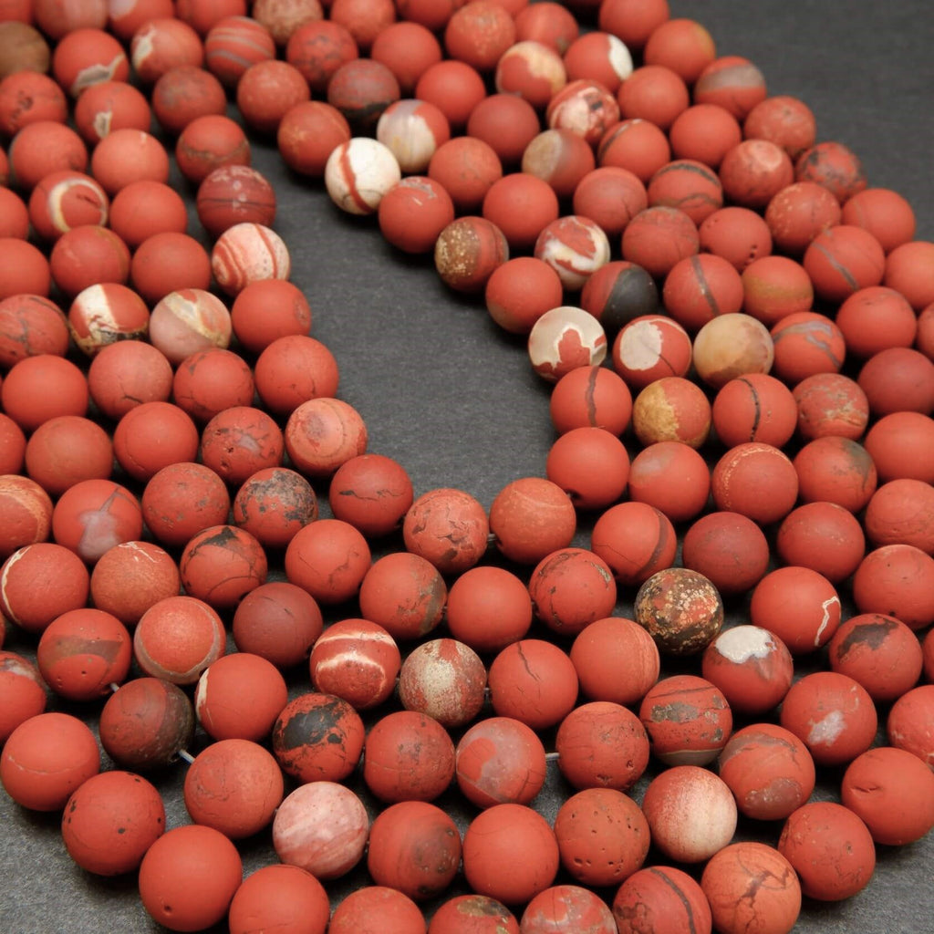 String of red marbled beads on a dark surface