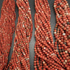 Multiple strands of red and brown beads on a gray background