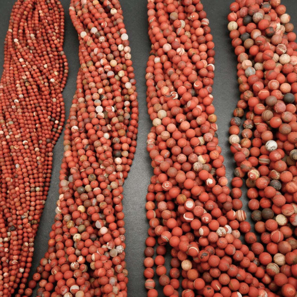 Multiple strands of red and brown beads on a gray background